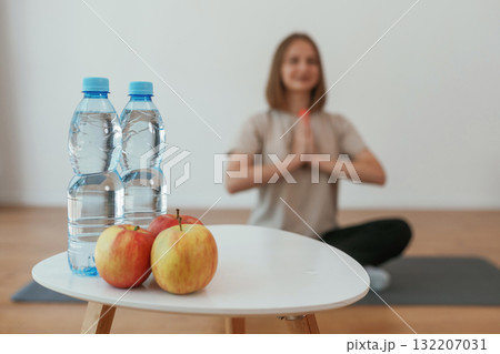 Young woman is sitting on the yoga mat. Conception of healthy eating, apples 132207031