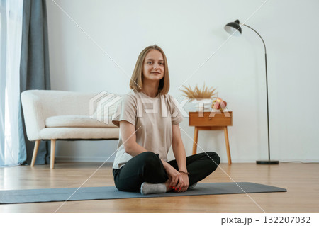 Young woman is sitting on the yoga mat. Conception of healthy eating, apples Young woman is sitting on the yoga mat. Conception of healthy eating, apples 132207032