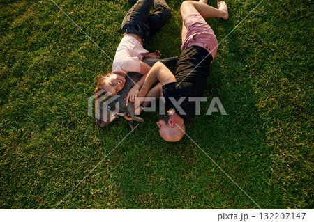 Top view, lying on the grass. Man and woman are with dog on the field Top view, lying on the grass. Man and woman are with dog on the field 132207147
