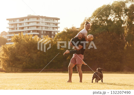 Girlfriend is with soccer ball. Man and woman are with dog on the field 132207490