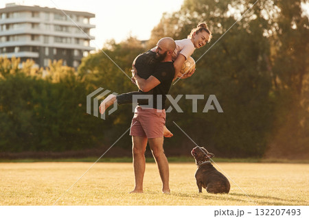 Girlfriend is with soccer ball. Man and woman are with dog on the field Girlfriend is with soccer ball. Man and woman are with dog on the field 132207493