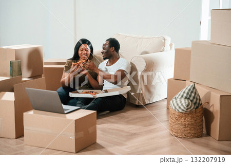 Tasty pizza, sitting and eating. African American couple are moving into new house Tasty pizza, sitting and eating. African American couple are moving into new house 132207919