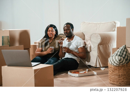 Drinking water and eating pizza. African American couple are moving into new house 132207928