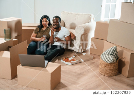 Drinking water and eating pizza. African American couple are moving into new house 132207929