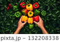 Colorful bell peppers being arranged by hands among fresh green leaves 132208338