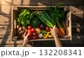 Fresh vegetables being arranged in a wooden crate at a bright market 132208341
