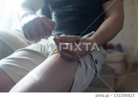 A man injects himself with adrenaline into his thigh during anaphylactic shock. First aid for allergies, emergency medical care for an allergic reaction. 132208823
