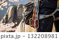Professional rock climbing gear with colorful carabiners and rope attached to climber harness against desert canyon background 132208981
