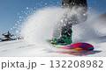 Snowboarder making sharp turn creating dramatic powder snow spray explosion on mountain slope with traditional Asian pagoda building visible in background on sunny winter day 132208982
