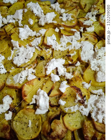 Sliced potatoes with cottage cheese baking in oven tray Sliced potatoes with cottage cheese baking in oven tray 132209080