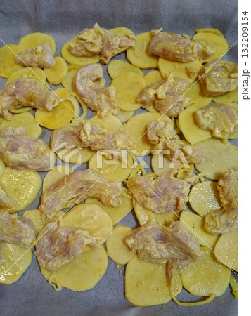 Raw chicken meat and sliced potatoes with spice marinade on baking tray Raw chicken meat and sliced potatoes with spice marinade on baking tray 132209154