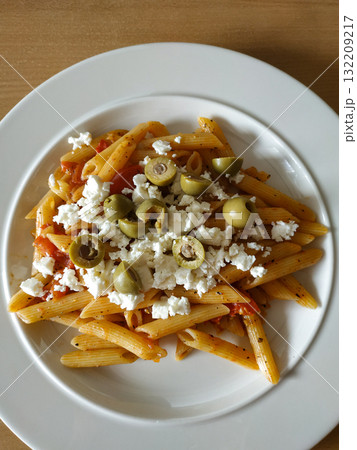 Penne pasta dish with tomatoes, olives and feta cheese on white plate healthy dinner Penne pasta dish with tomatoes, olives and feta cheese on white plate healthy dinner 132209217