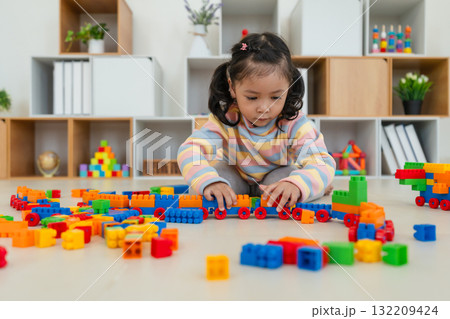 toddler girl playing building blocks or plastic bricks toy at home toddler girl playing building blocks or plastic bricks toy at home 132209424