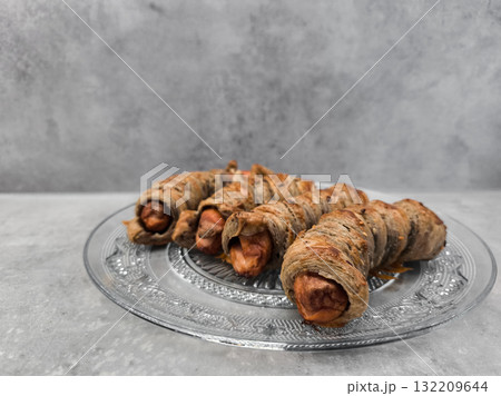 Sausage rolls wrapped in whole wheat leafy multigrain dough resting on glass plate copy space 132209644