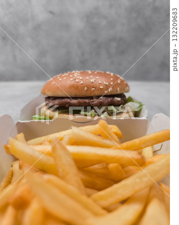 Hamburger with sesame seeds and french fries resting in cardboard containers galentines day Hamburger with sesame seeds and french fries resting in cardboard containers galentines day 132209683