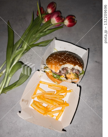 Cheeseburger and french fries with red tulips on gray table galentines day Cheeseburger and french fries with red tulips on gray table galentines day 132209696