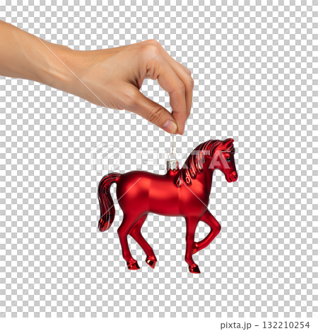Hand holding classic red glass horse christmas ornament , festive holiday decoration isolated on a soft background Hand holding classic red glass horse christmas ornament , festive holiday decoration isolated on a soft background 132210254