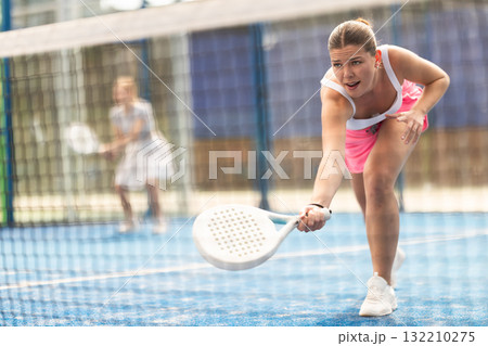 Young woman playing doubles padel tennis 132210275