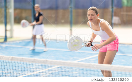Woman standing behind net on tennis court Woman standing behind net on tennis court 132210290