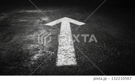 White arrow painted on dark asphalt road surface pointing forward symbolizing direction and progress in minimalistic style 132210567
