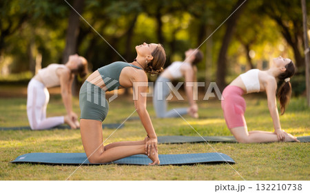 Yoga lesson visitors girls perform Ushtrasana in park 132210738
