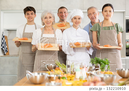 Smiling female chef posing along with cooking course participants 132210910