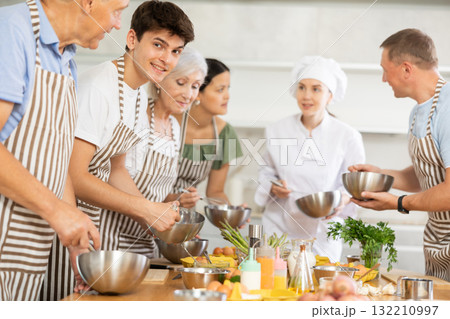 Young female cook teaches to cook group of people Young female cook teaches to cook group of people 132210997
