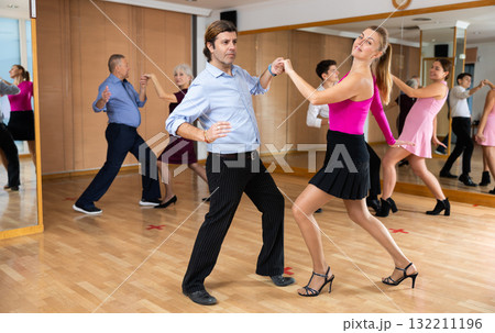 Couple of dancers rehearsing ballroom dances in dance studio Couple of dancers rehearsing ballroom dances in dance studio 132211196