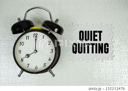 Jigsaw puzzle with a missing piece with "Quiet Quitting" and alarm clock on white background 132211476