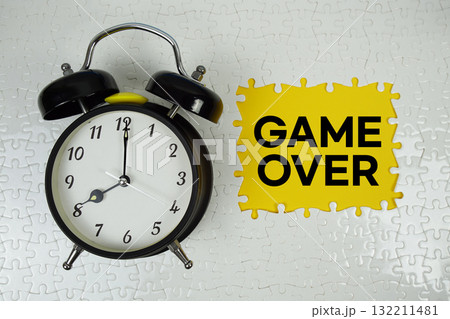 Jigsaw puzzle with a missing piece with "Game Over" and alarm clock on yellow background 132211481