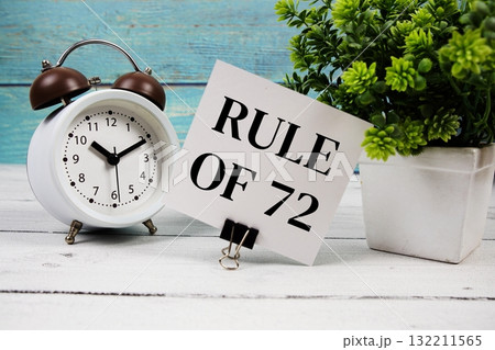 Rule of 72 text written on paper card with alarm clock on wooden background Rule of 72 text written on paper card with alarm clock on wooden background 132211565