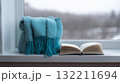 Cozy Winter Moment with Open Book and Soft Blanket on Windowsill 132211694