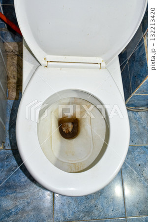 Dirty toilet bowl with hard water stains and rust deposits in bathroom 132213420