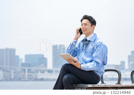 電話をする作業服の男性　タブレット 132214940