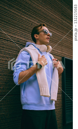 Young man in light blue hoodie with white sweater and headphones outdoors Young man in light blue hoodie with white sweater and headphones outdoors 132215083
