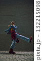 Man posing mid-step in denim jacket on cobblestone city street 132215098