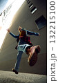 Man jumping in city alley wearing denim jacket and red checkered shirt 132215100