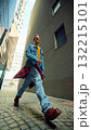 Man walking between tall buildings in denim jacket and sunglasses 132215101