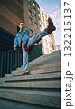 Stylish man kicking leg on city stairs in denim jacket and orange sunglasses 132215137