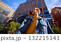 Young man in denim jacket smiling talking on smartphone among modern buildings 132215141