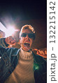 Stylish man biting silver chain under sunlight in expressive streetwear look 132215142