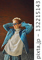 Smiling man in denim jacket enjoying sunlight with relaxed confidence 132215143