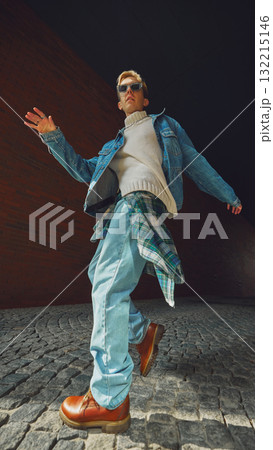 Young man in denim jacket walking confidently under city arch with modern attitude 132215146