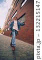 Smiling man in jeans and sunglasses walking through modern city street 132215147