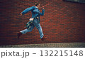 Man in denim outfit running along brick wall expressing freedom and motion 132215148