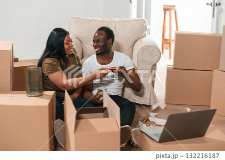Delicious pizza, sitting by the laptop. African American couple are moving into new house 132216187