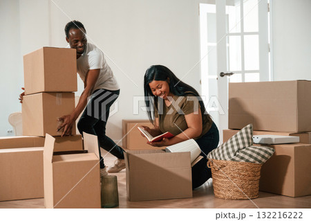Guy is holding lot of boxes. African American couple are moving into new house Guy is holding lot of boxes. African American couple are moving into new house 132216222