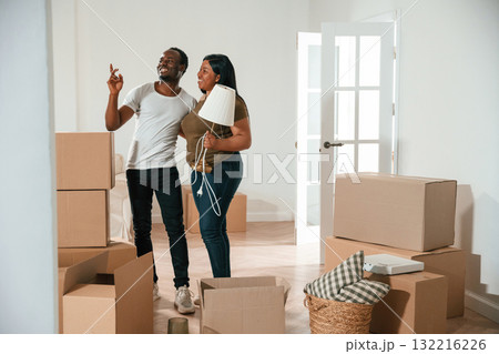 Woman is holding lamp. African American couple are moving into new house 132216226