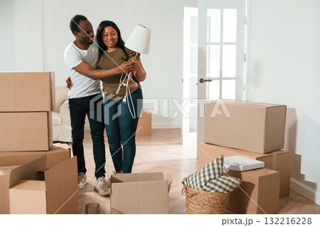 Woman is holding lamp. African American couple are moving into new house Woman is holding lamp. African American couple are moving into new house 132216228