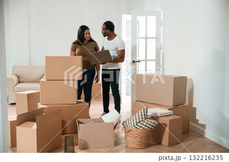 Wireless device, using laptop. African American couple are moving into new house Wireless device, using laptop. African American couple are moving into new house 132216235